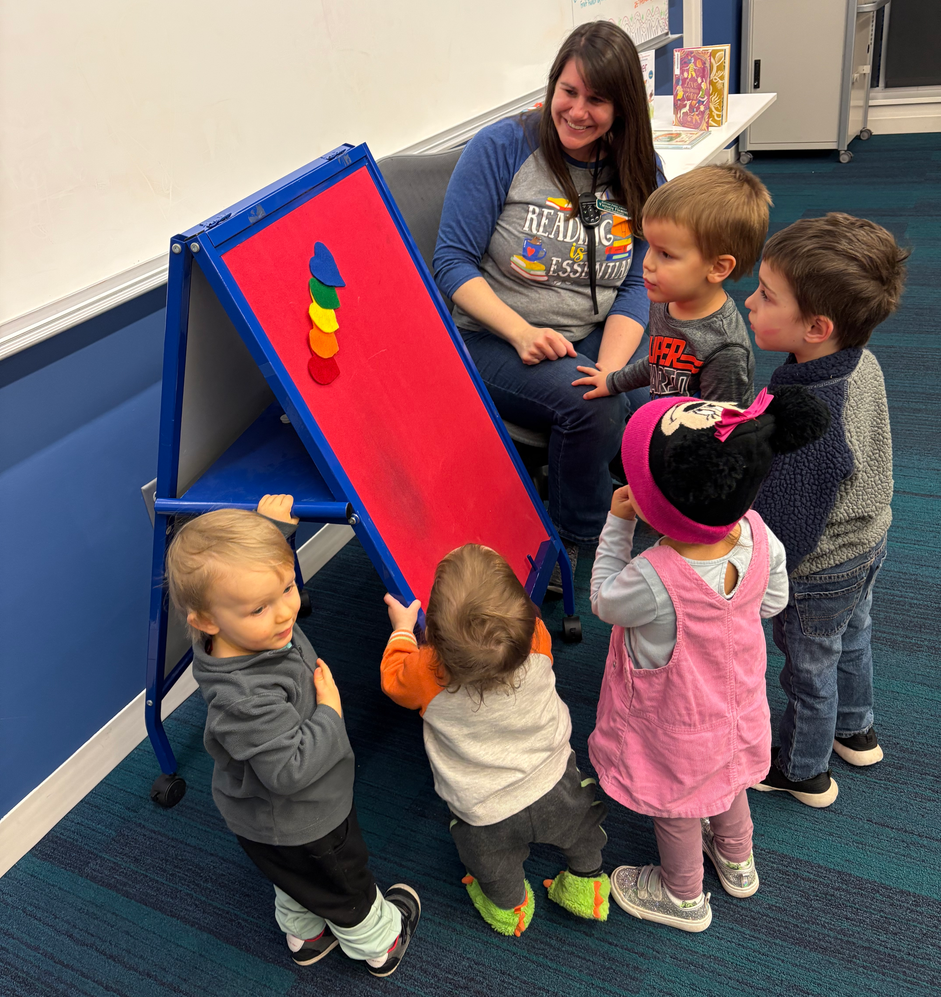 Five toddlers around a felt board with a librarian smiling down
