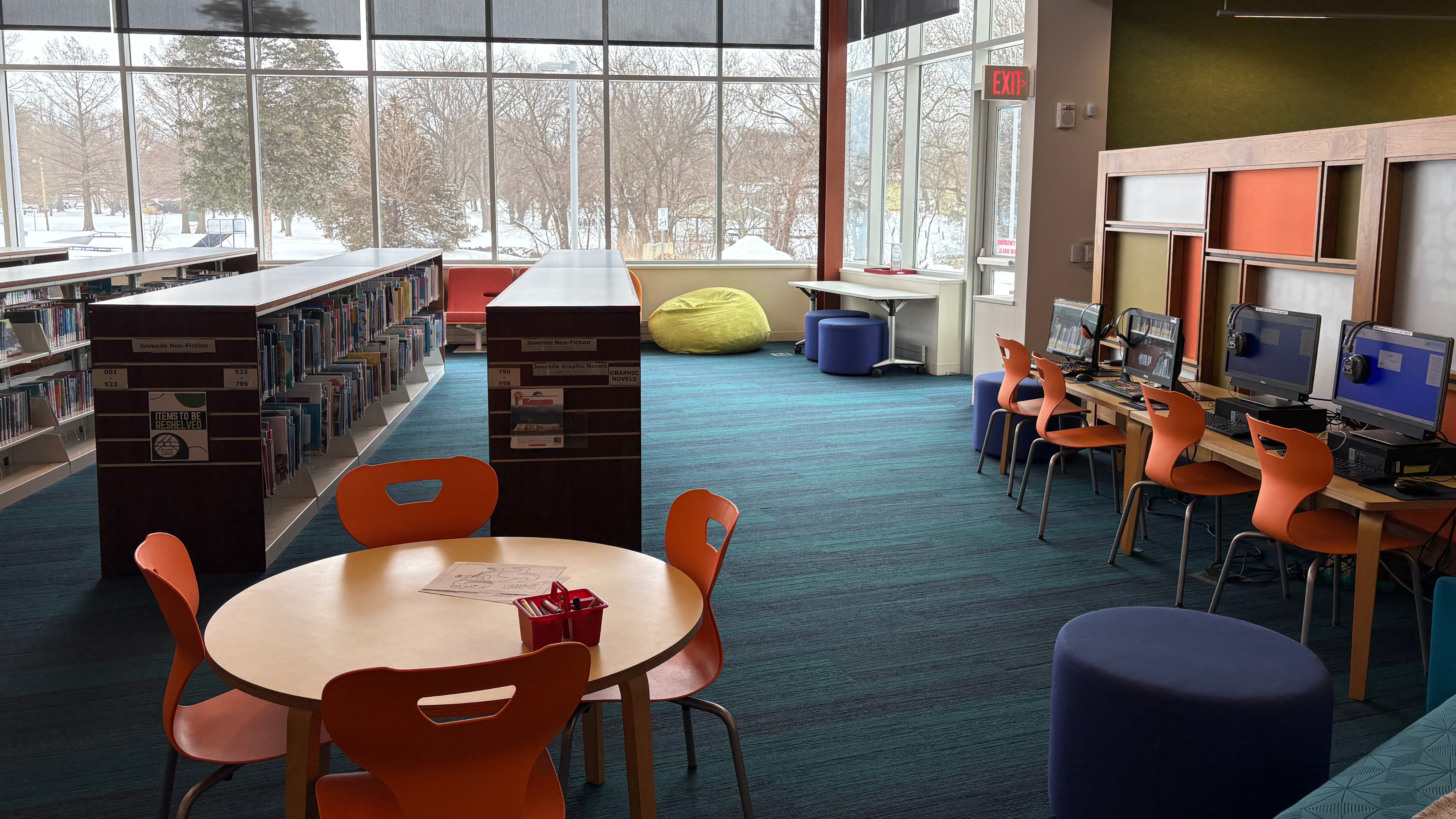 Youth library space with table and three computers with large window in the background