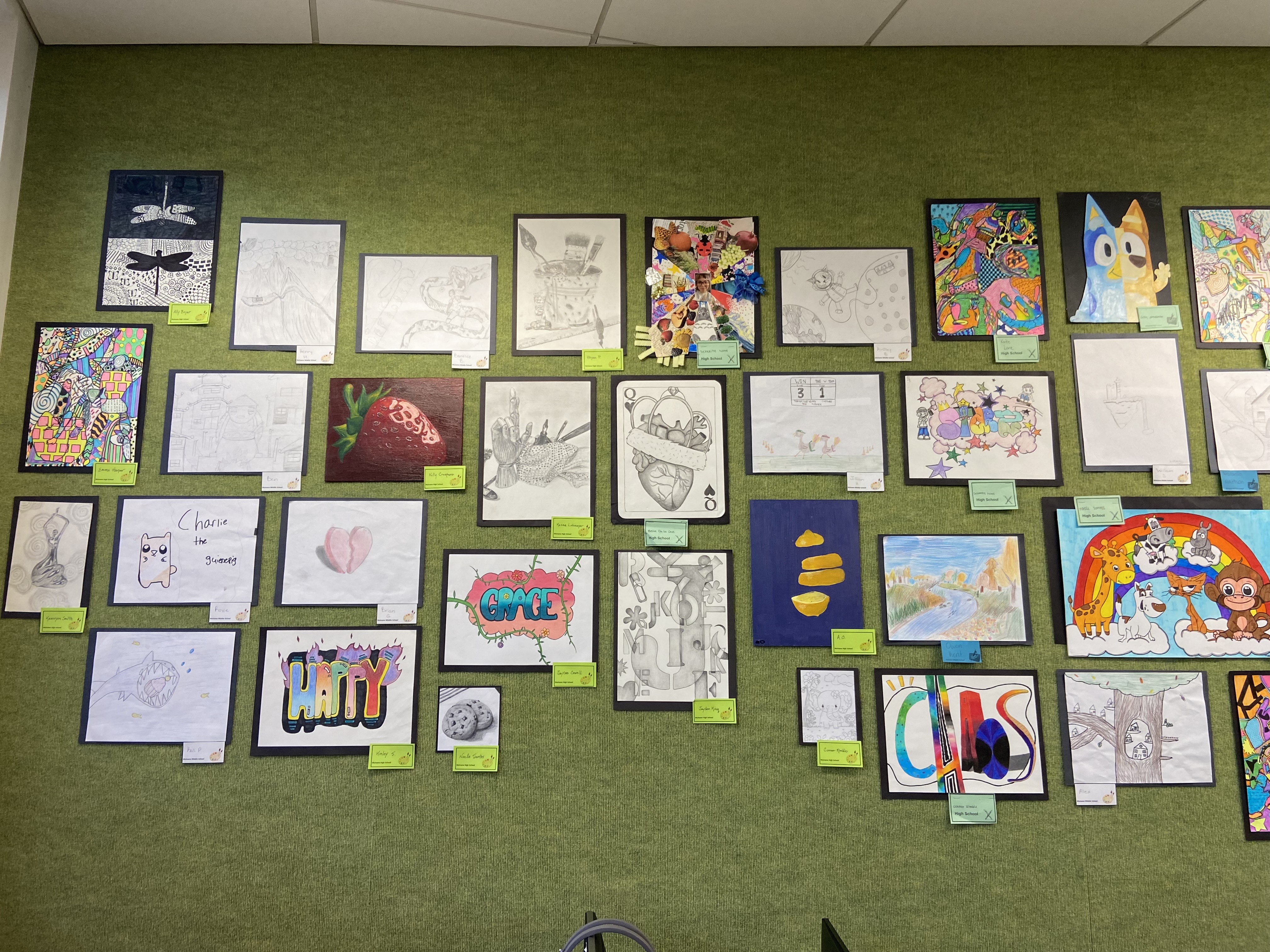 variety of art on green wall with labels