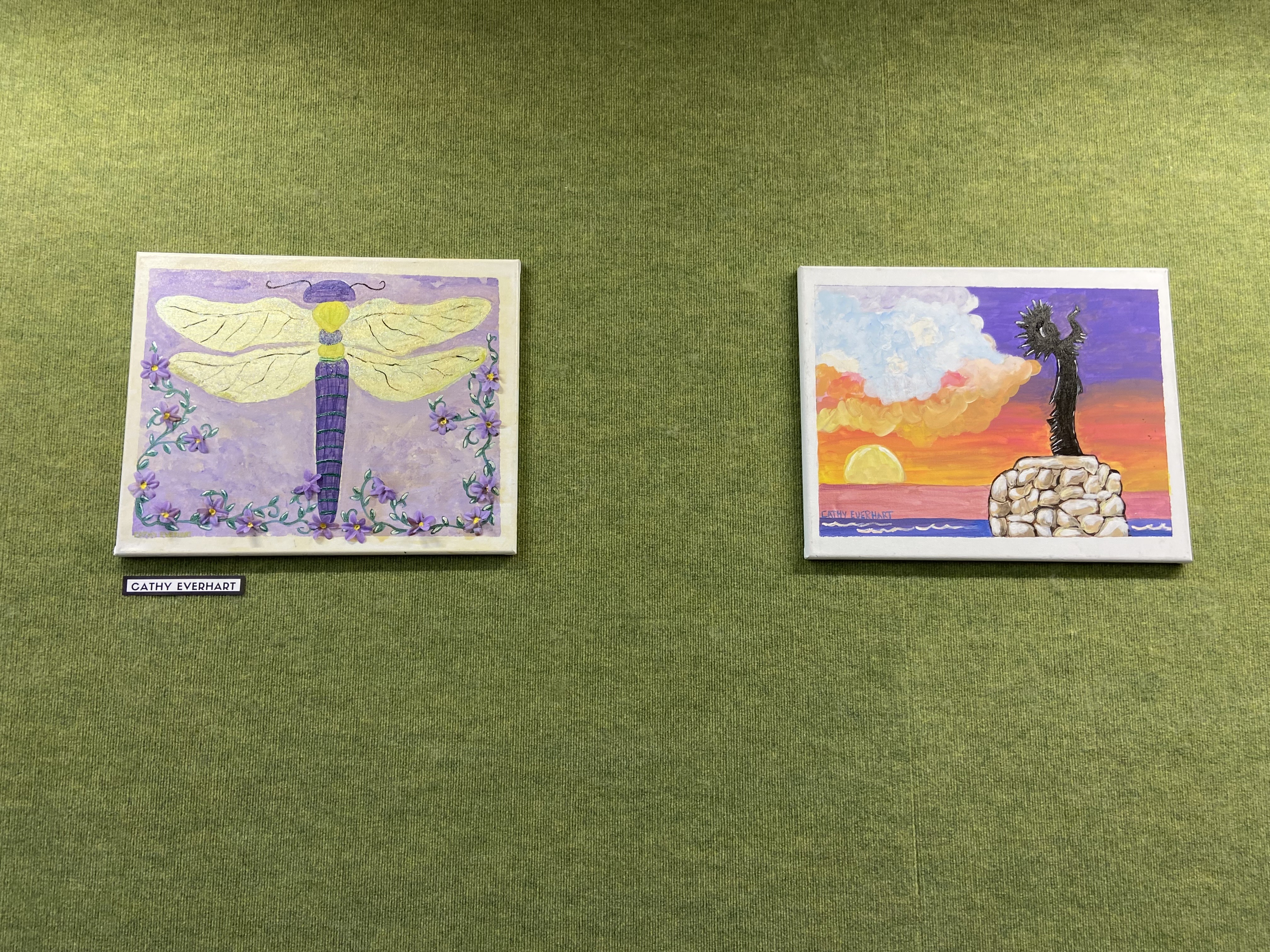 green wall with colorful pieces of canvas art