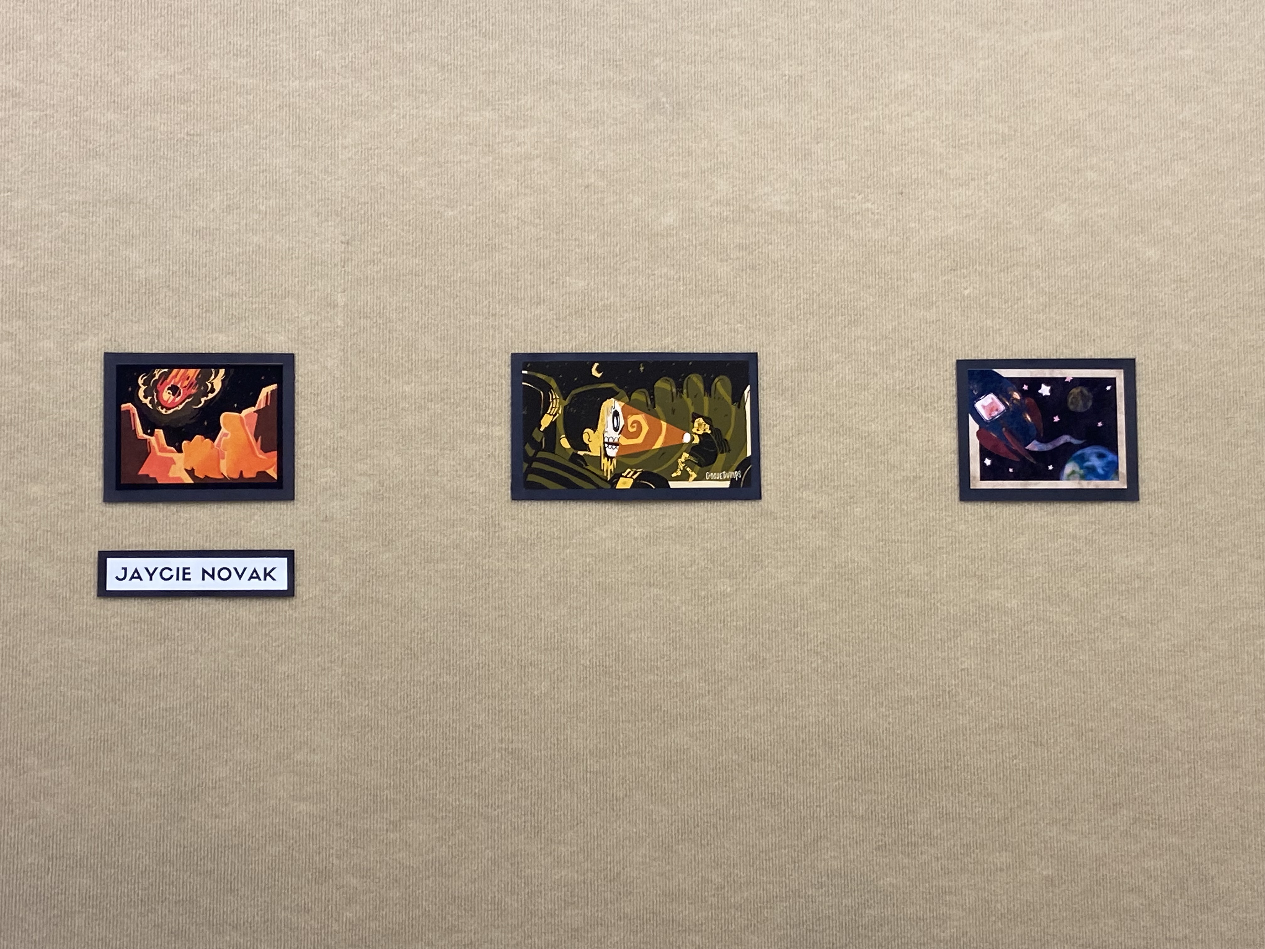 three matted drawings on a beige wall