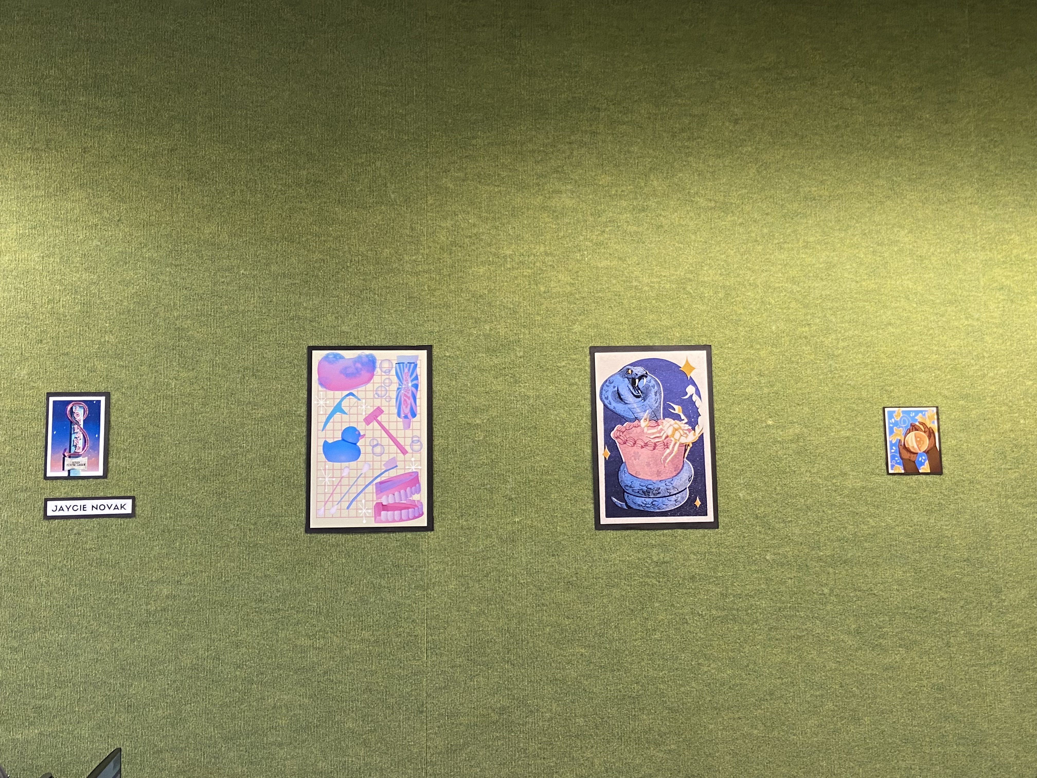 four matted drawings on a green wall