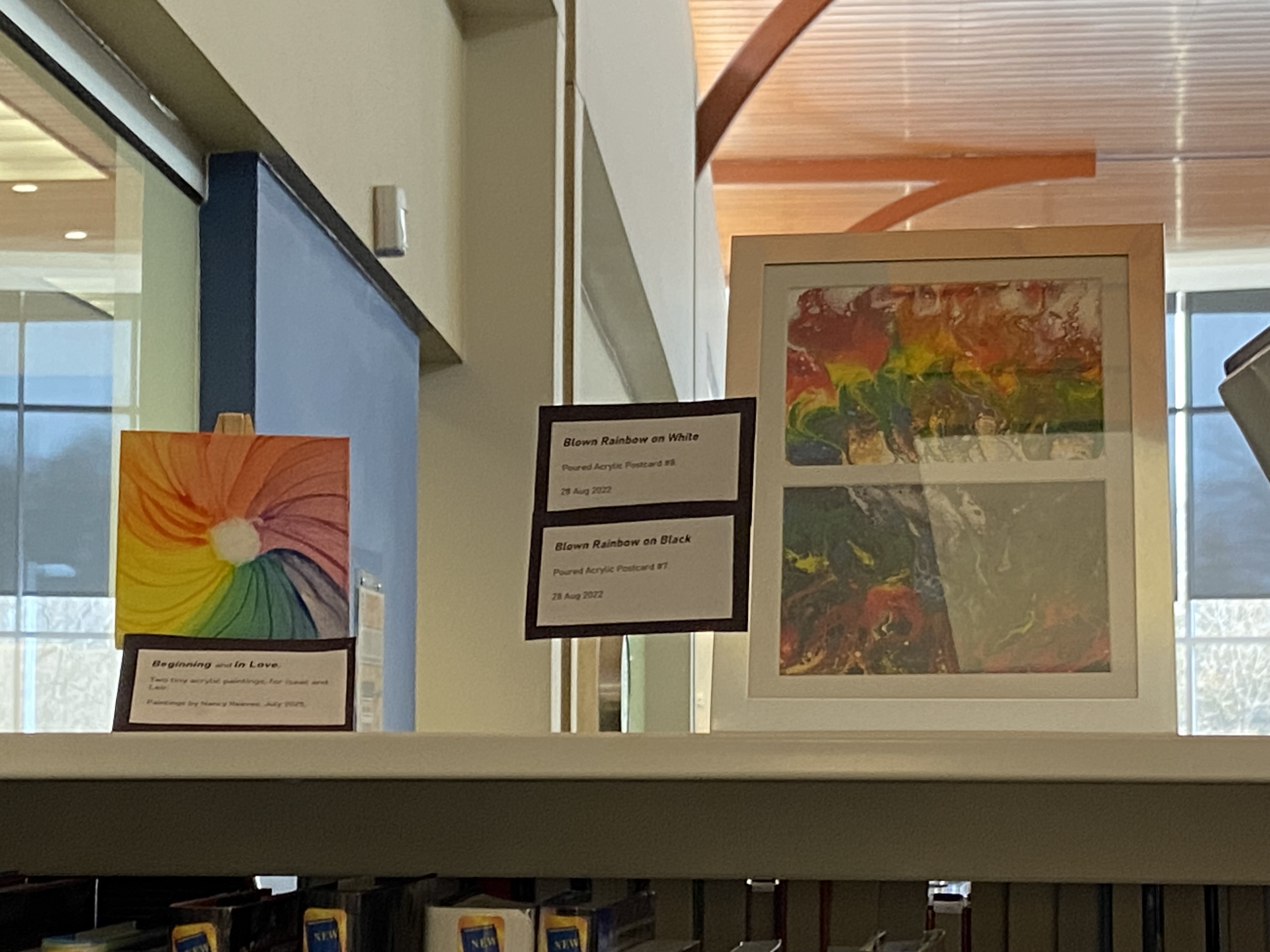 small rainbow canvas art and framed art on bookshelf