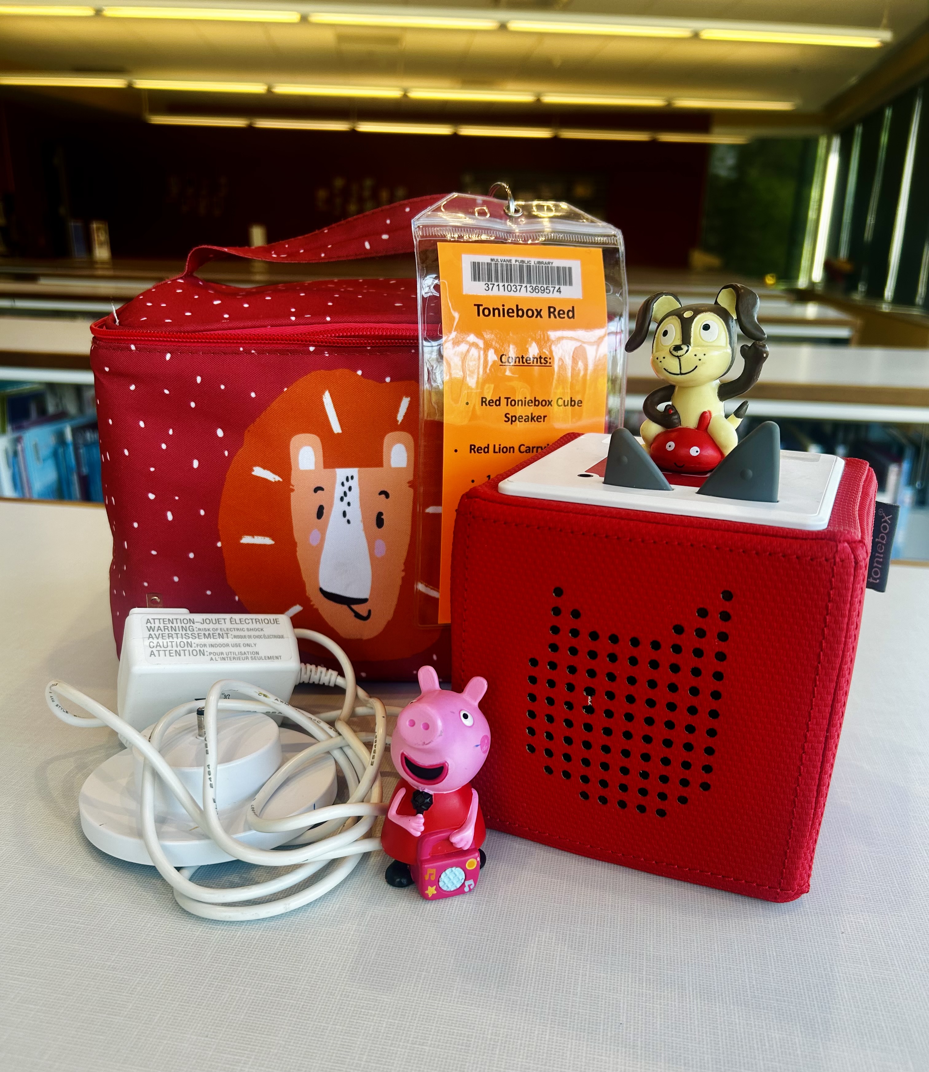 Red toniebox with red lion carrying case, peppa pig figurine, playtime puppy figurine, and instruction sheet