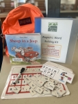 Orange backpack with book, magnet bord, magnetic letter tiles and work cards
