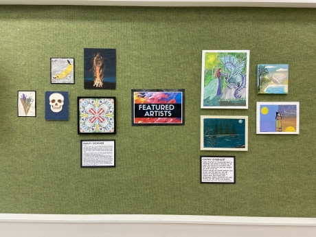 green wall with colorful sign saying featured artist, with several pieces of flat art